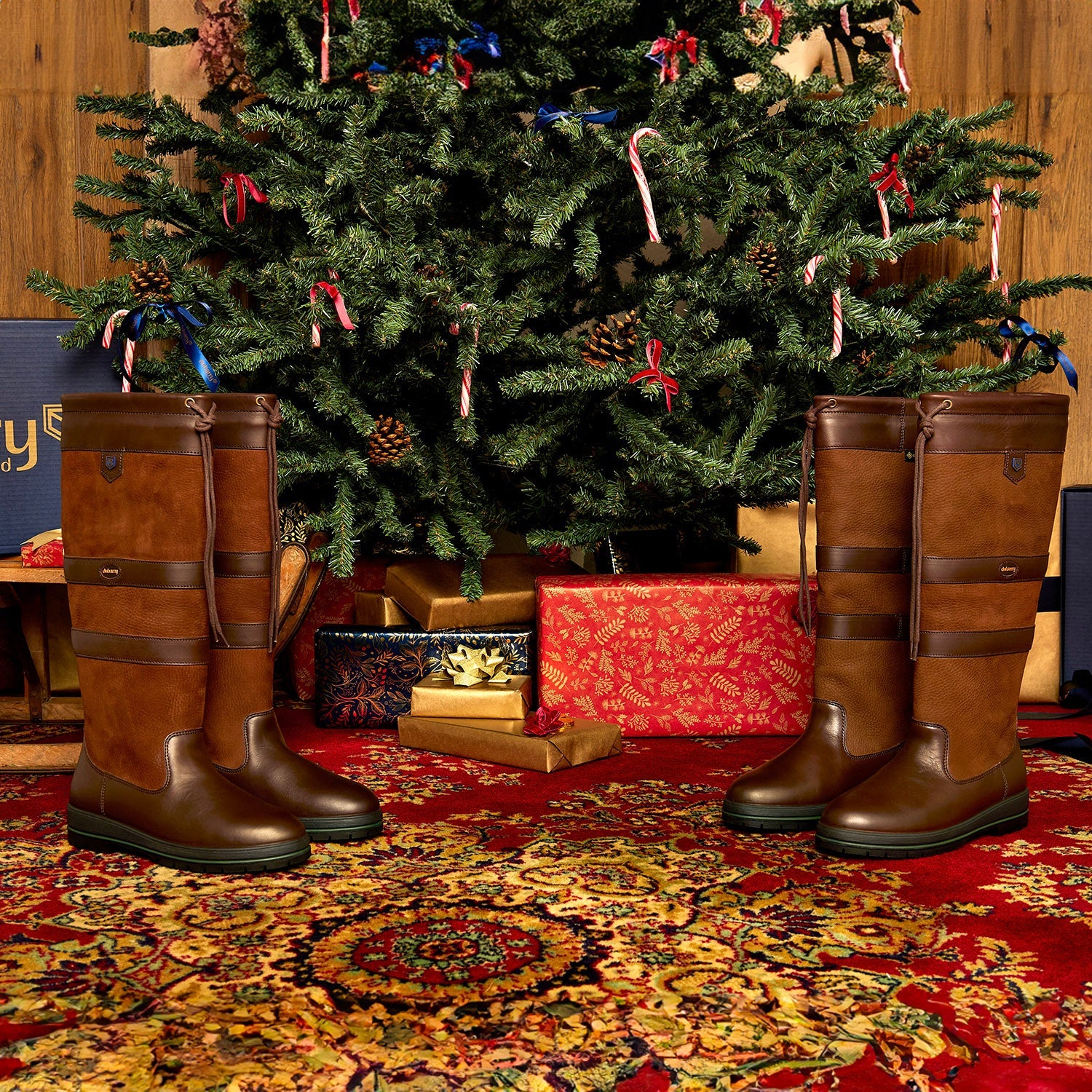 Pair of Galway Leather Waterproof Breathable Country Boots positioned in front of a Christmas tree, with one pair on each side, creating a festive setting.