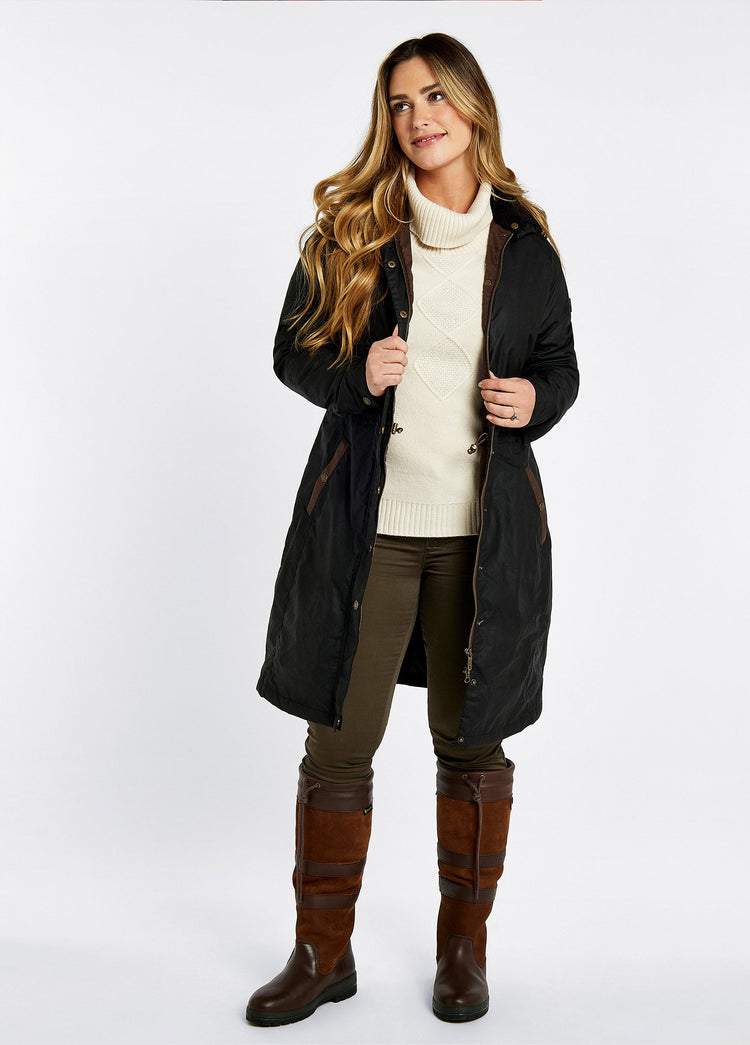 On Model image of a woman wearing wider calf fitting Ladies Dubarry knee-high walnut brown leather Galway Country Boot with laced top. She is also wearing a navy wax jacket, cream knitted jumper and green honeysuckle jeans.